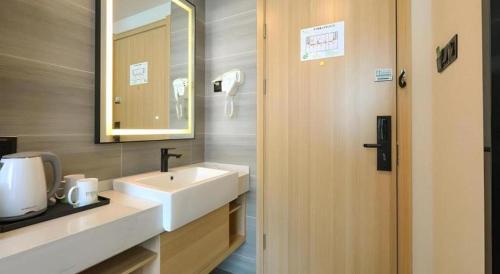 a bathroom with a sink and a mirror at Vatica Hotel Huangshan South Gate Terminal Station in Huangshan Scenic Area