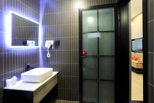 a bathroom with a white sink and a mirror at Jun Hotel Shanxi Linfen Hongdong County Dahuaishu Xungen Jizhuyuan in Linfen