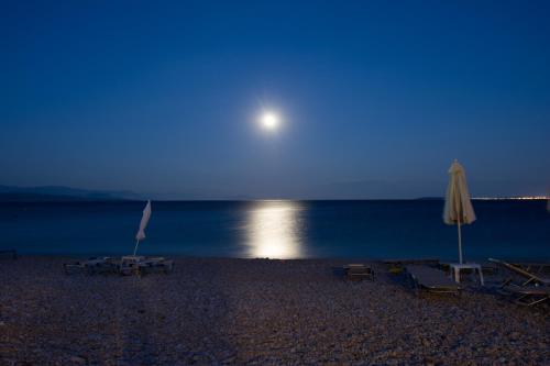 a beach with chairs and an umbrella and the moon at Renata Rooms & Studios in Barbati