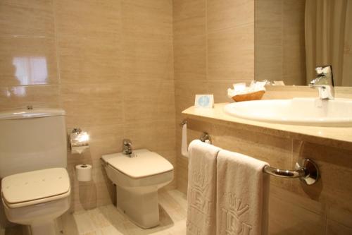 a white toilet sitting next to a sink in a bathroom at Oca Ipanema Hotel in Vigo