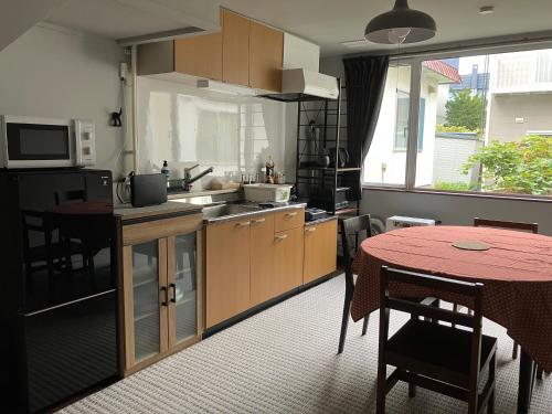 a kitchen with a table and a red tableablish at SNS guest house Sapporo in Sapporo