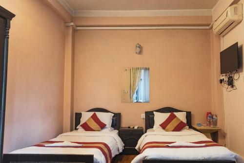two beds in a room with a window at Nepalaya Hotel Thamel 17 Kwabhal in Kathmandu