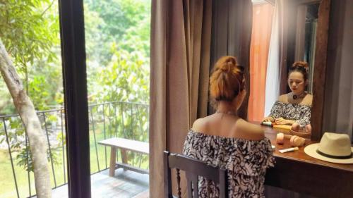 a woman looking at her reflection in a mirror at YesHue Eco Waterfall Retreat in Hue