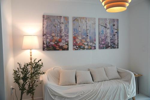 a white couch in a room with three paintings on the wall at WhiteTreeHouse 