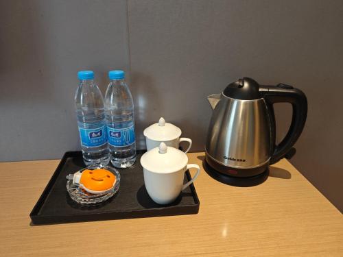 ein Tablett mit 2 Flaschen Wasser und einem Wasserkocher in der Unterkunft Sainan Hotel, Guangzhou Zhongda Lujiang Subway Station Branch in Guangzhou