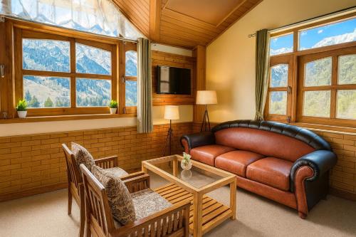 a living room with a couch and a table at Snow Clad Riverview Hotel & Resort, Manali in Manāli