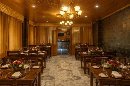 a restaurant with wooden tables and chairs and a chandelier at Snow Clad Riverview Hotel & Resort, Manali in Manāli