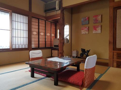 a dining room with a wooden table and white chairs at Shibu Onsen Koishiya Ryokan in Yamanouchi