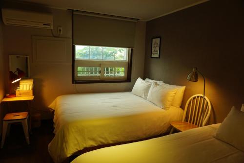 a hotel room with two beds and a window at Grim Garden Guesthouse in Yeosu