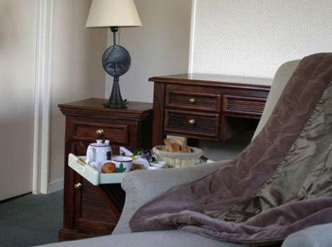 a living room with a chair and a desk with a lamp at Logis Hotel Les Sapins in Le Ménil