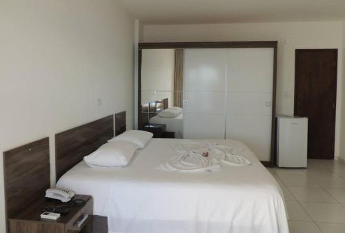 um quarto com uma grande cama branca e um espelho em Salinas Praia Hotel em Salinas da Margarida