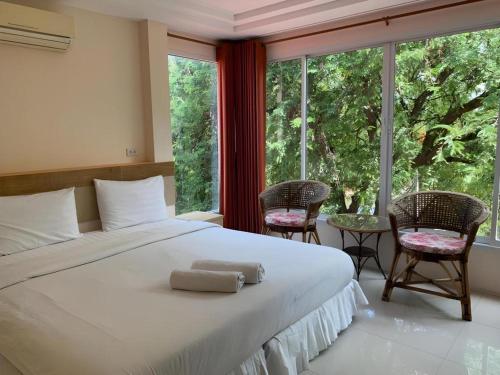 a bedroom with a bed with two chairs and a large window at Magic House Hostel in Hua Hin