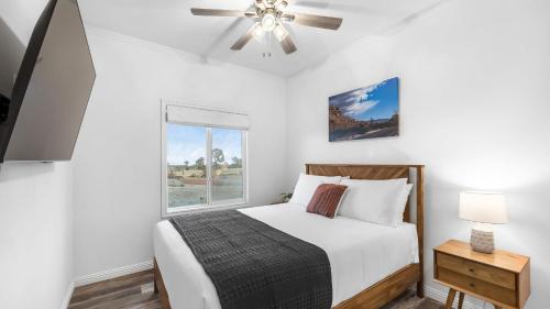 a bedroom with a bed with a ceiling fan and a window at Pool Spa Pickleball Piano Near Pioneertown Harmony House by AvantStay in Yucca Valley