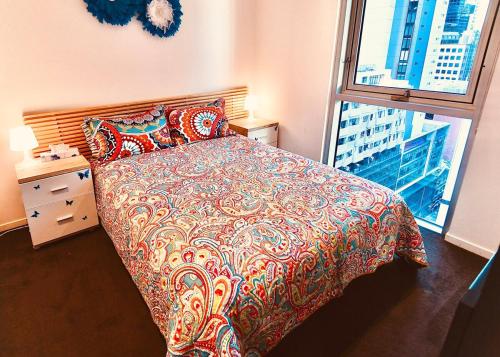 a bedroom with a bed with a colorful comforter and a window at Melborne Collins Home in Melbourne