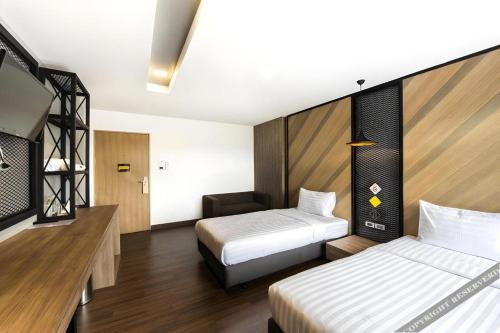 a hotel room with two beds and a chair at The Circle Hotel in Buriram