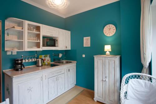 a kitchen with white cabinets and a blue wall at Trzy Siostry in Krynica Zdrój
