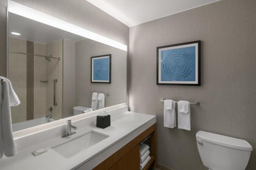 a bathroom with a sink and a toilet and a mirror at Hyatt Place Denver Cherry Creek in Denver