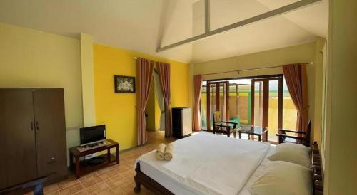 a bedroom with a large white bed and yellow walls at Aroma Pai Spa Hotel in Pai