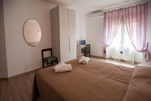Schlafzimmer mit einem Bett und einem Fenster mit rosa Vorhängen in der Unterkunft Carillon in Civitavecchia