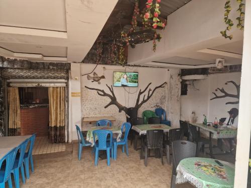a restaurant with tables and chairs and a tree on the wall at Complexe la samaritaine 2 in Yaoundé