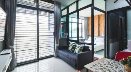 a room with a couch and a bed and windows at The Smart Hostel in Nakhon Ratchasima