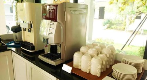 a kitchen counter with a coffee maker and stacks of plates at Rittiboon Vintage Hotel in Phrae
