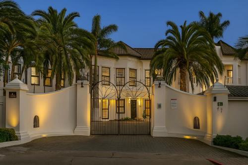 Una gran casa blanca con palmeras delante. en Ivory Room Lableva Court, en Lusaka