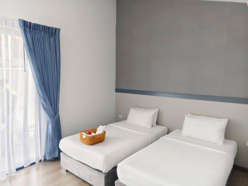 two beds in a room with a basket on them at Rapina House in Mai Khao Beach