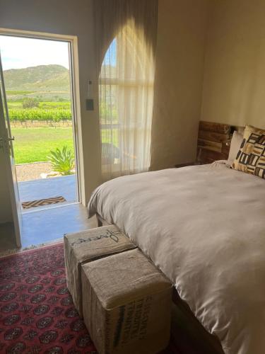 une chambre avec un grand lit et une grande fenêtre dans l'établissement The Schoolhouse at Meulplaas, à Montagu