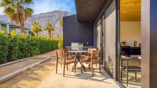 a patio with a table with chairs and a laptop on it at Blackhaus Suites by AvantStay in Palm Springs