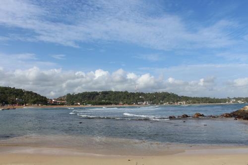 a beach with the ocean and rocks in the water at Santori Unawatuna in Unawatuna