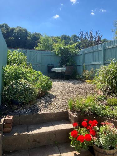 a garden with a fence and a table and flowers at Character Cottage in Usk in Usk