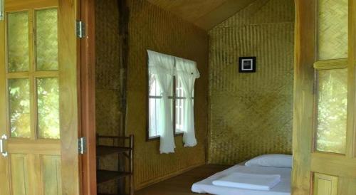 una piccola stanza con un letto e una finestra di Chiang Dao Hut a Chiang Dao