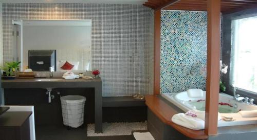 a bathroom with a tub and a sink and a mirror at Hua Hin Avenue Hotel in Hua Hin