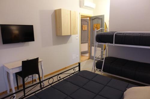 a room with two bunk beds and a table and a tv at Rooms Maison 3 Magnoni in Trieste