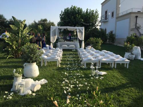 a group of white chairs in the grass with a table at Casale del Murgese Country Resort in Savelletri di Fasano