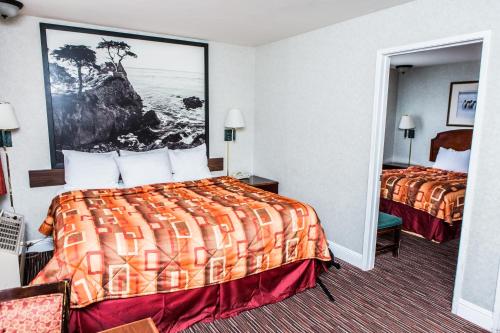 a hotel room with two beds and a painting on the wall at Pelican Inn in Monterey