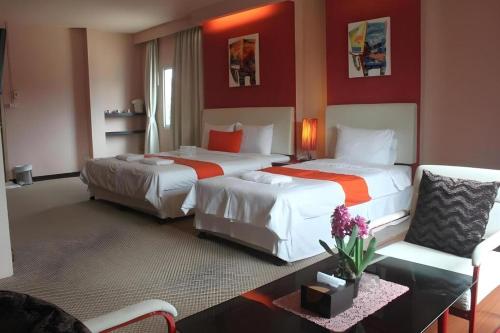 due letti in una stanza d'albergo con pareti rosse di Cactus Resort & Hotel a Khon Kaen