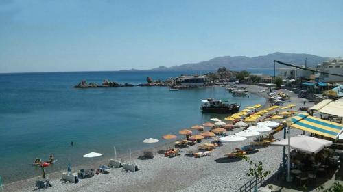 a beach with umbrellas and a group of boats at Haraki Blue Pearl in Haraki