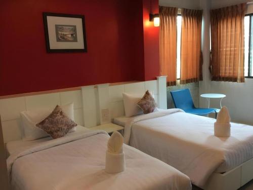 a hotel room with two beds and a blue chair at Waenpetch place Hotel in Ubon Ratchathani