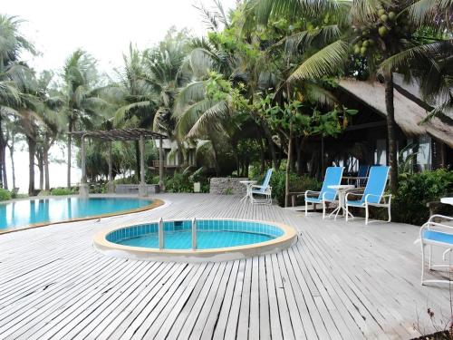 eine Terrasse mit zwei Pools und Stühlen und Palmen in der Unterkunft Chivaree Hotel and Resort in Chanthaburi