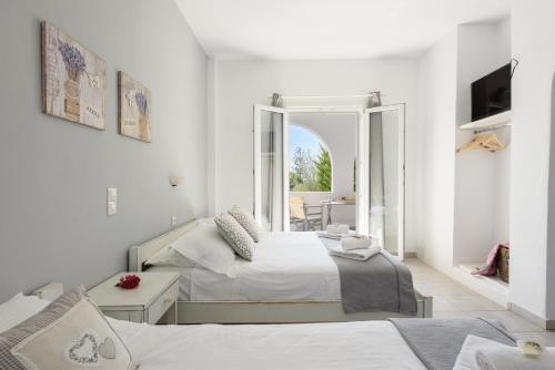 a white bedroom with two beds and a balcony at Anixis Studios Aliki Paros in Aliki