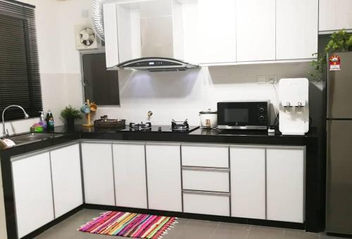 a kitchen with white cabinets and a black counter top at Homestay Putrajaya Near Lake, Dataran Putrajaya - Boulevard Putrajaya, Shaftsbury Alamanda & Masjid Putra in Putrajaya