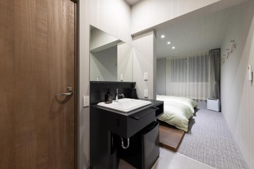 a bathroom with a sink and a bed in a room at Hotel Yatsu in Komatsu