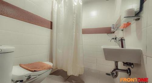 a bathroom with a shower and a toilet and a sink at Front One Hotel Jayapura in Jayapura