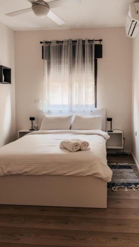 a bedroom with a large white bed with a window at סוף העולם שמאלה in Idan