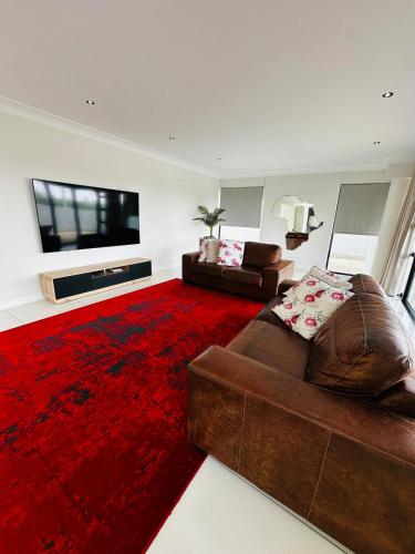 a living room with a brown couch and a red rug at Duinen Suites in Walvis Bay