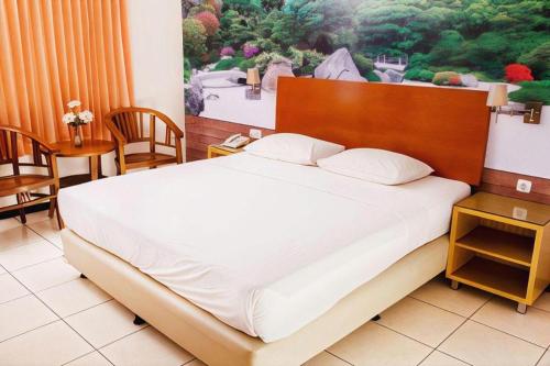 a bedroom with a large bed with a wooden headboard at Hotel Kings Kudus in Kudus