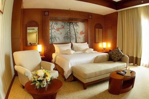 a hotel room with a bed and a couch and chairs at Labersa Grand Hotel &Convention Center in Pekanbaru