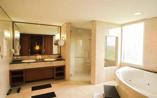 a bathroom with two sinks and a tub and a large mirror at Labersa Grand Hotel &Convention Center in Pekanbaru